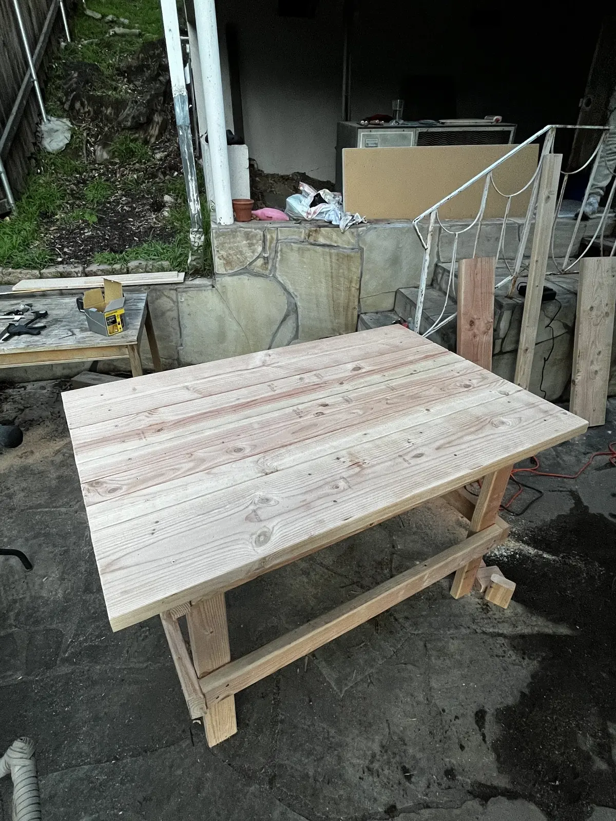 A finished wooden table made from planed planks, with a simple trestle base.