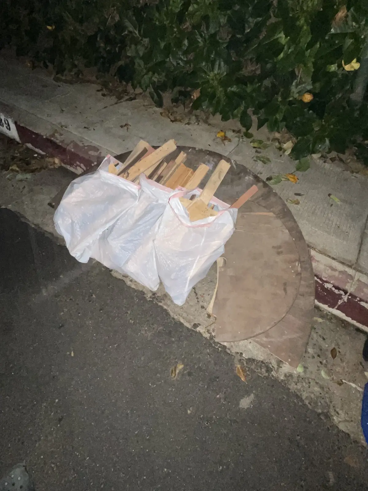A rustic round wooden table on a patio at night, next to potted cacti and a white iron fence.