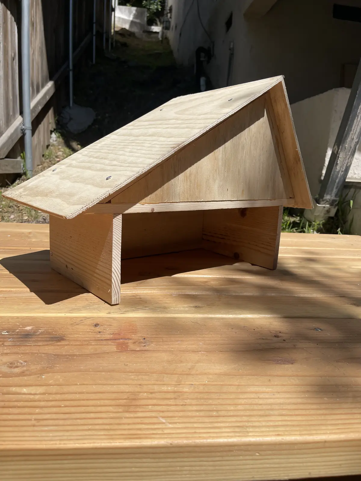 A small wooden A-frame roof structure on a deck, without side walls yet.